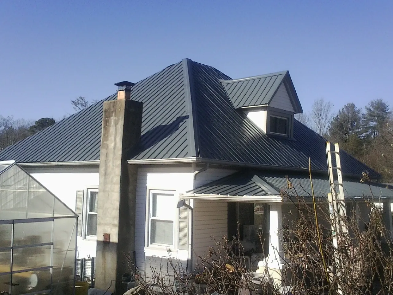 Dark blue standing seam metal roof on a white farmhouse with dormer — Slate & Tile Roof Repair by Roofing Brothers in New Galilee