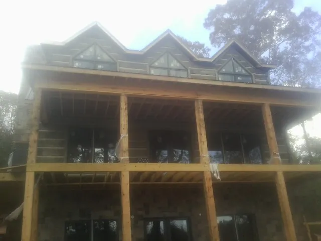 Dormers and porch framing on a large log home under construction — Roof Coating work by our crew in New Galilee