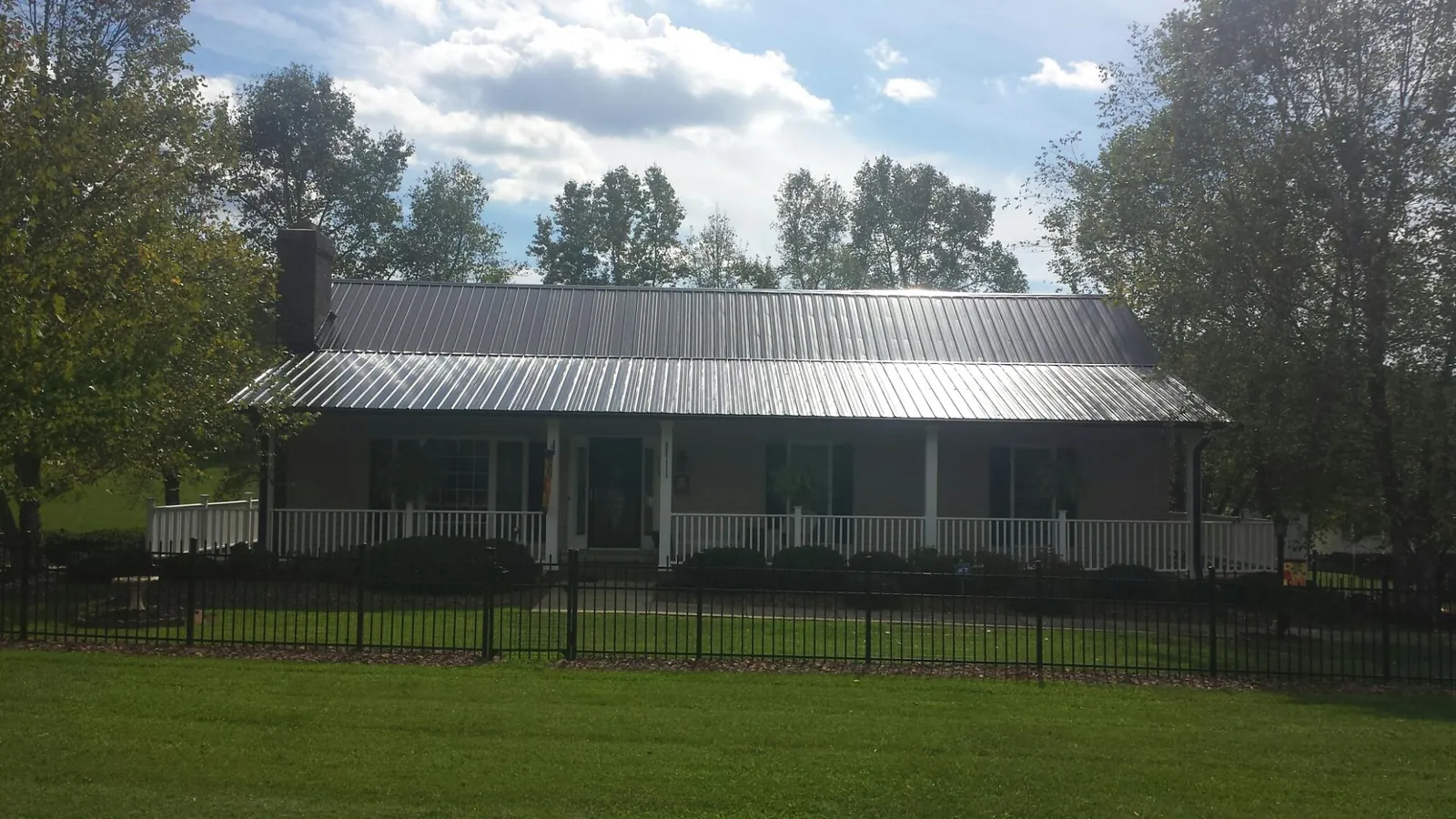 Gray metal roof on a brick ranch with a full width front porch — Gutter Guard Installation work by our crew in New Galilee