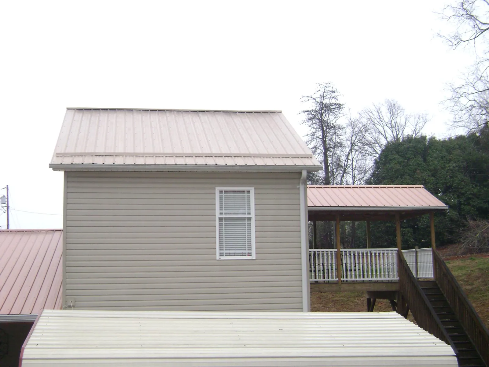 Tan metal roofs on a two story addition and attached porch, from a Roof Replacement job in New Galilee